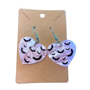 Spooky bat Halloween dangle earrings on an iridescent pink heart background